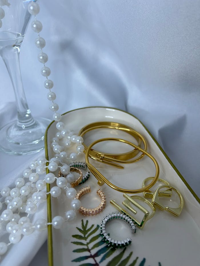 A stylish display of gold and pearl jewelry on a decorative tray.