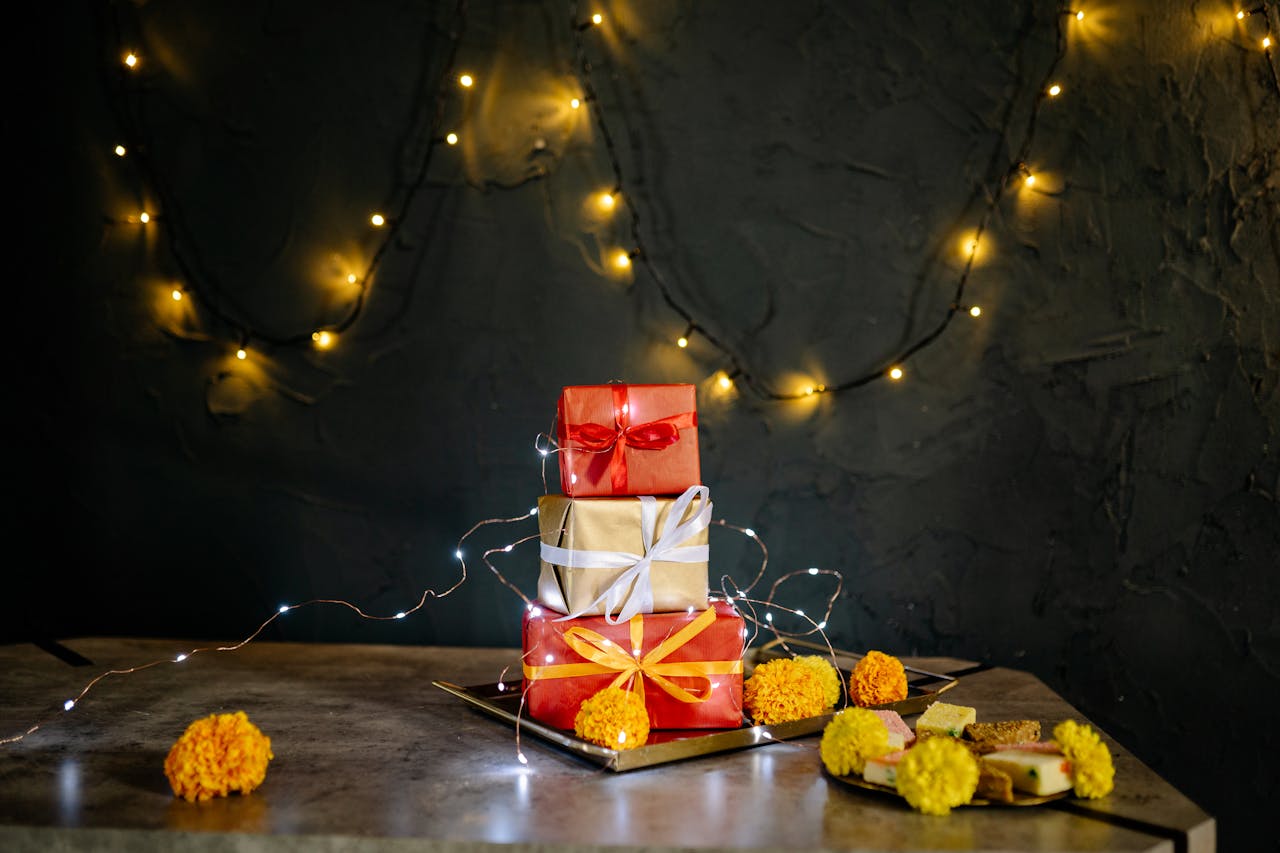 Stacked gift boxes with festive lights and marigolds on a table. Perfect for holiday celebrations.